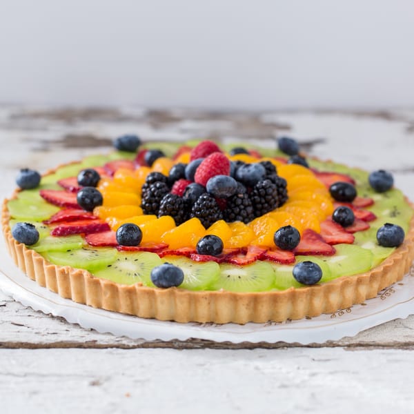 A vibrant fruit tart from Honeymoon Sweets, topped with kiwi, strawberries, blueberries, raspberries, and mandarins.