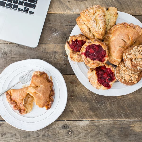 Assortment of Honeymoon Sweets pastries, including fruit tarts, scones, and muffins, on a rustic wooden table.