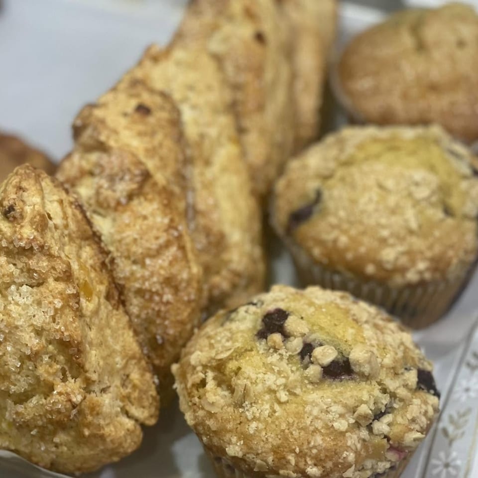Close-up of golden-brown scones with sugar crystals and blueberry muffins with streusel topping.